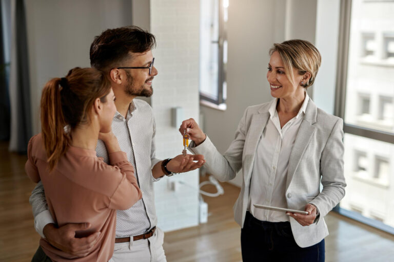 happy-real-estate-agent-giving-keys-couple-who-is-buying-their-new-home